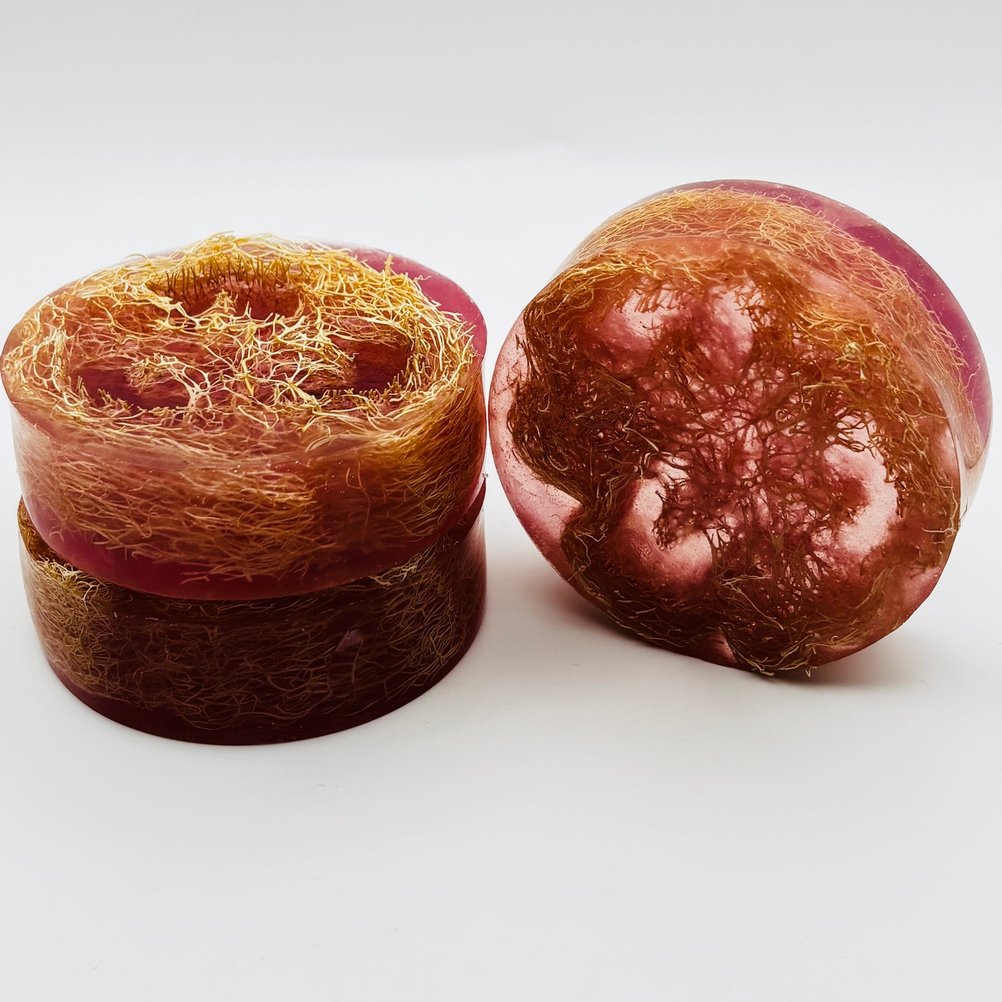 side view of three loofah soap bars scented with A thousand wishes fragrance oil, shimmering magenta colored mica, and organically grown loofahs
