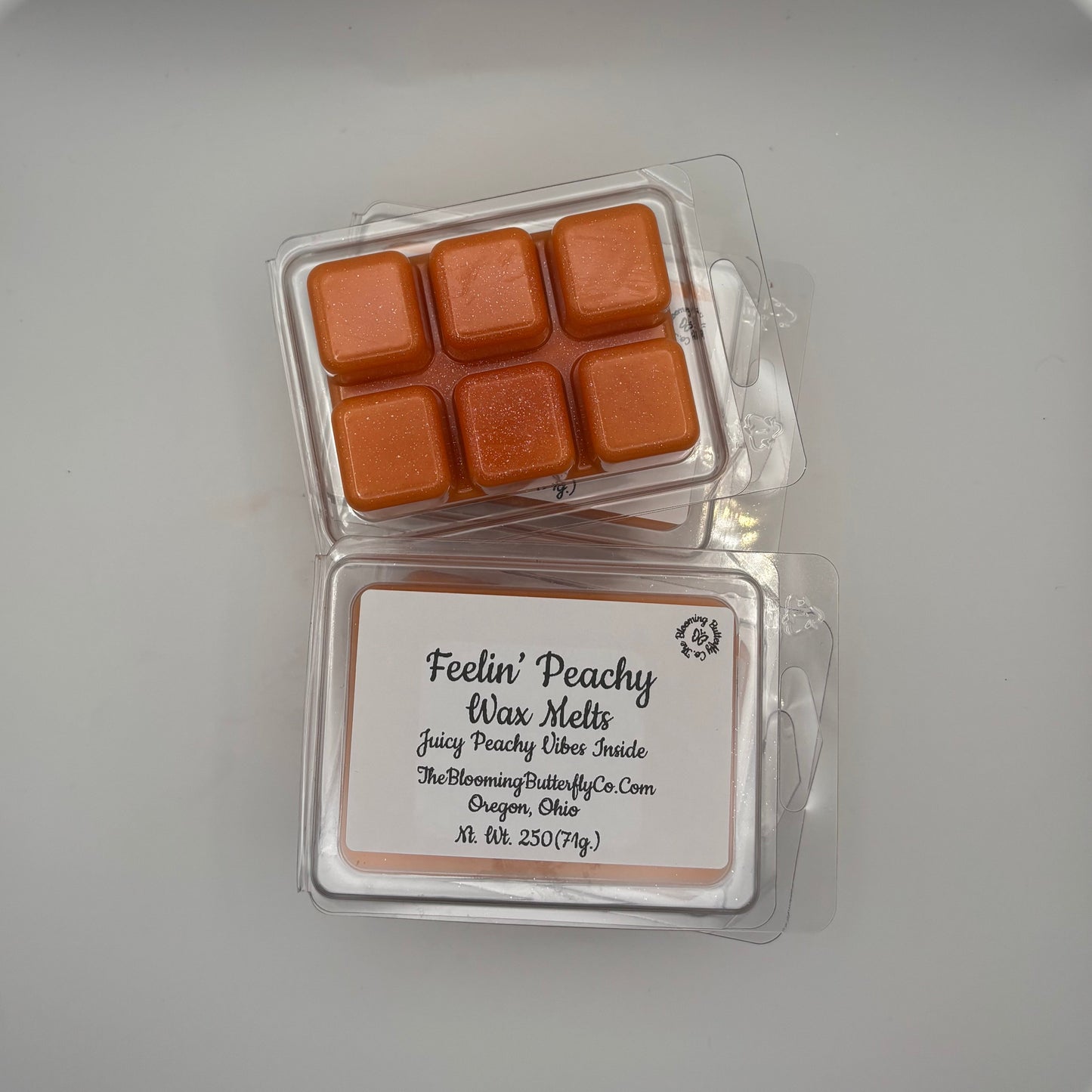shimmering orange peach scented wax melts in a 6 count clam shell with label made by the blooming butterfly company
