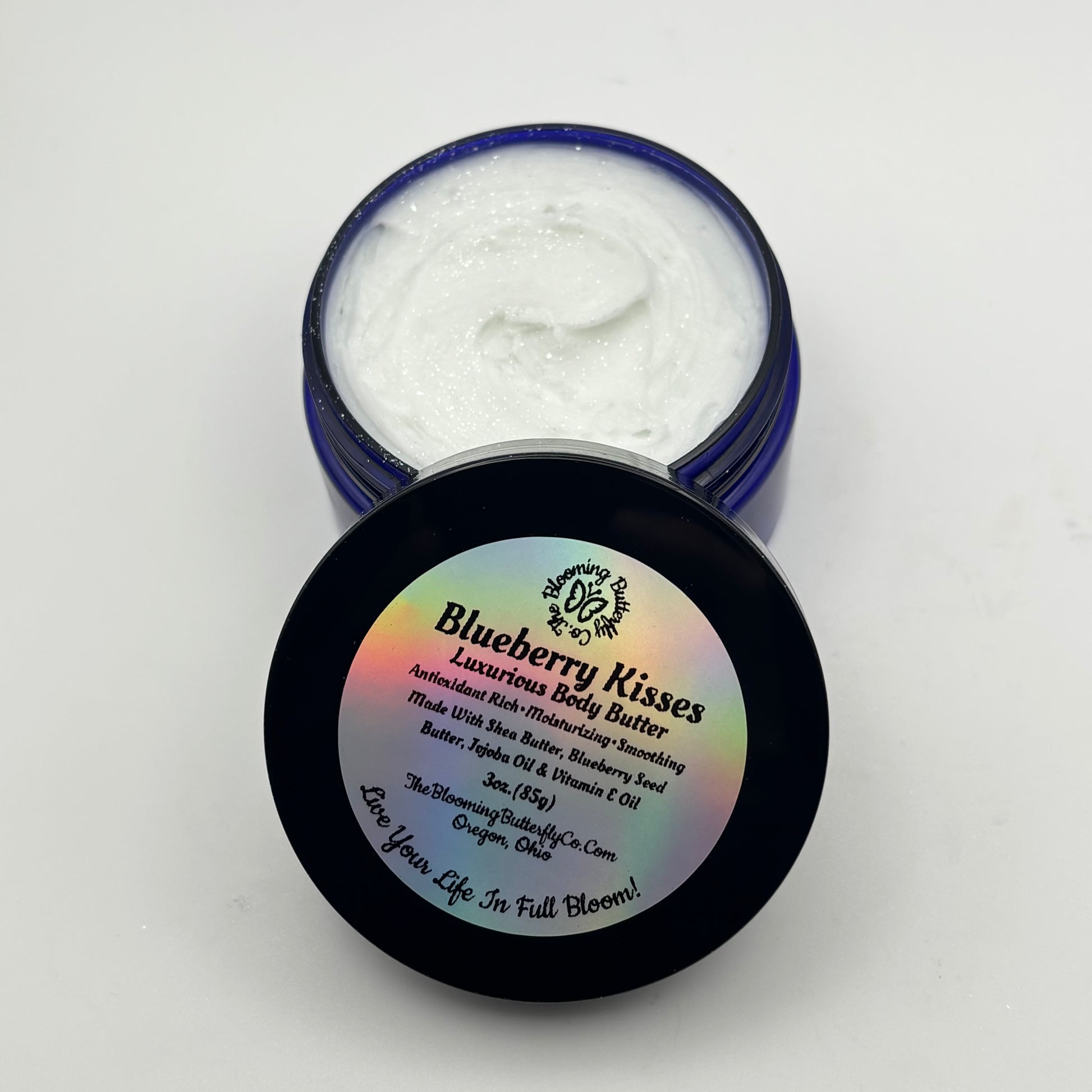 Three ounces of blueberry kisses luxuriousThree ounces of blueberry kisses luxurious body butter in a cobalt blue pet jar with a holographic label and white background handcrafted by the blooming butterfly company