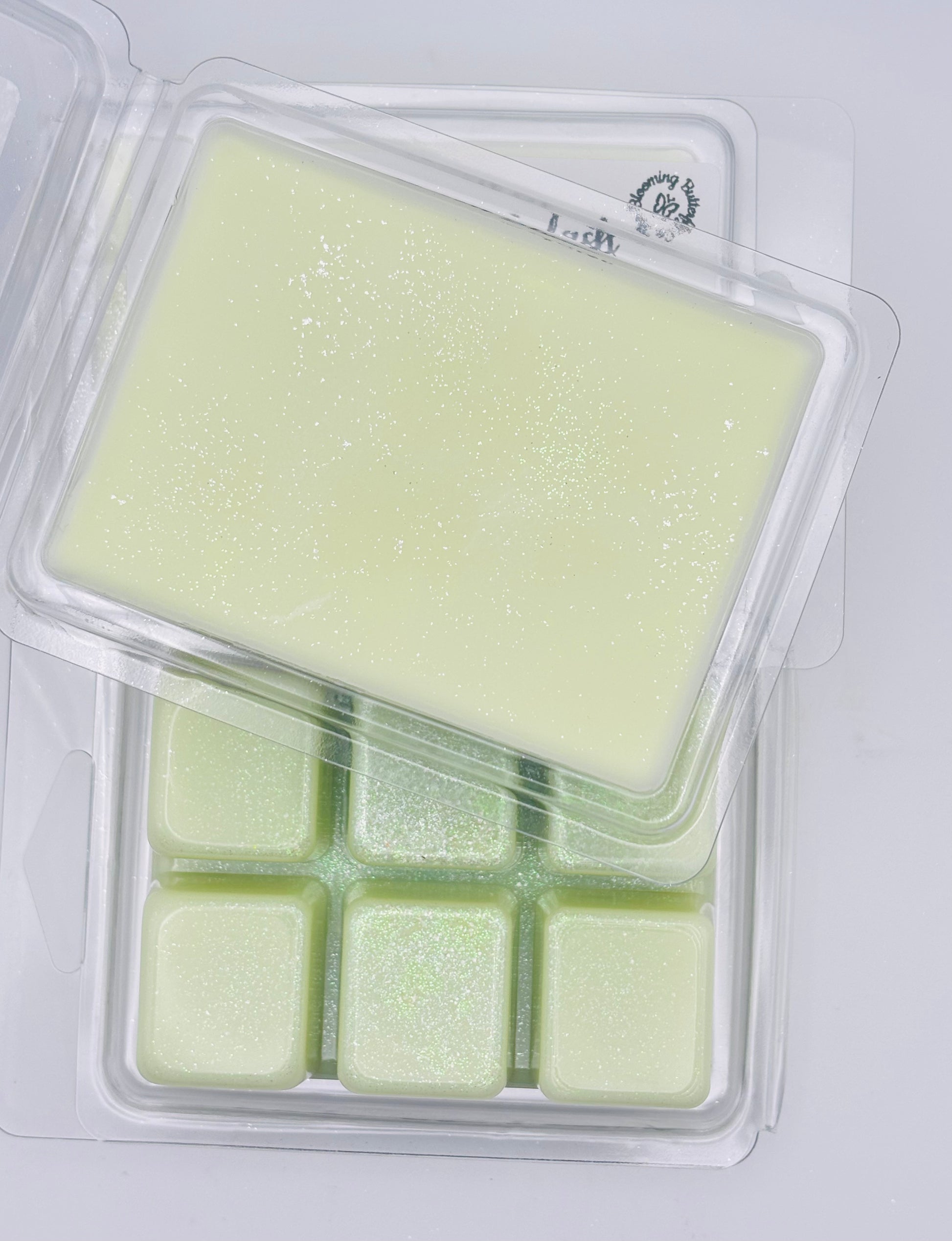 Packaged green blooming berry splash wax melts in a clear plastic container on a white background handcrafted by the blooming butterfly company