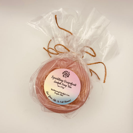 two round pink sparkling grapefruit loofah soap bars wrapped in cellophane with brown twine handcrafted by the blooming butterfly company
