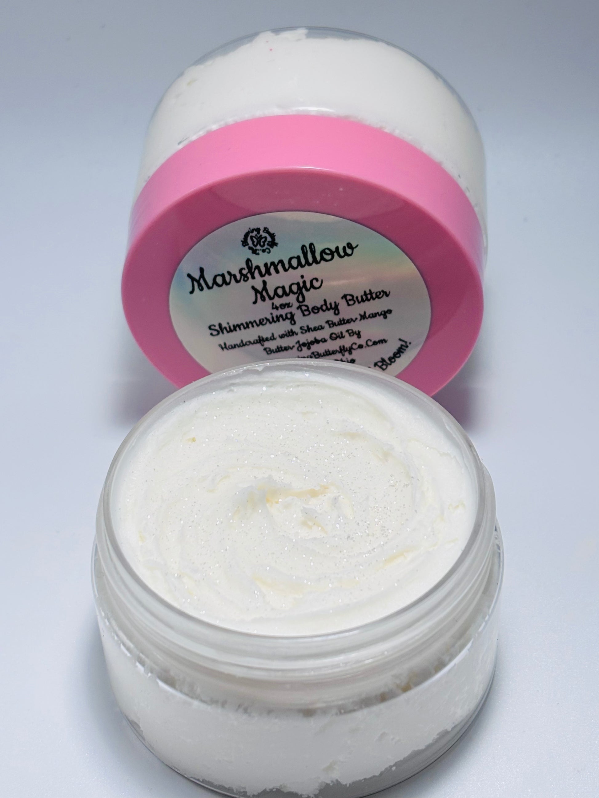 One clear jar of marshmallow magic, shimmering, whipped body butter with sparkles on top a pink lid with holographic label, handcrafted with mango and Shea, butters by the blooming butterfly company