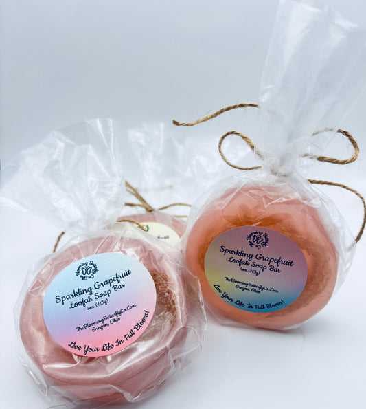 two round pink sparkling grapefruit loofah soap bars wrapped in cellophane with brown twine handcrafted by the blooming butterfly company
