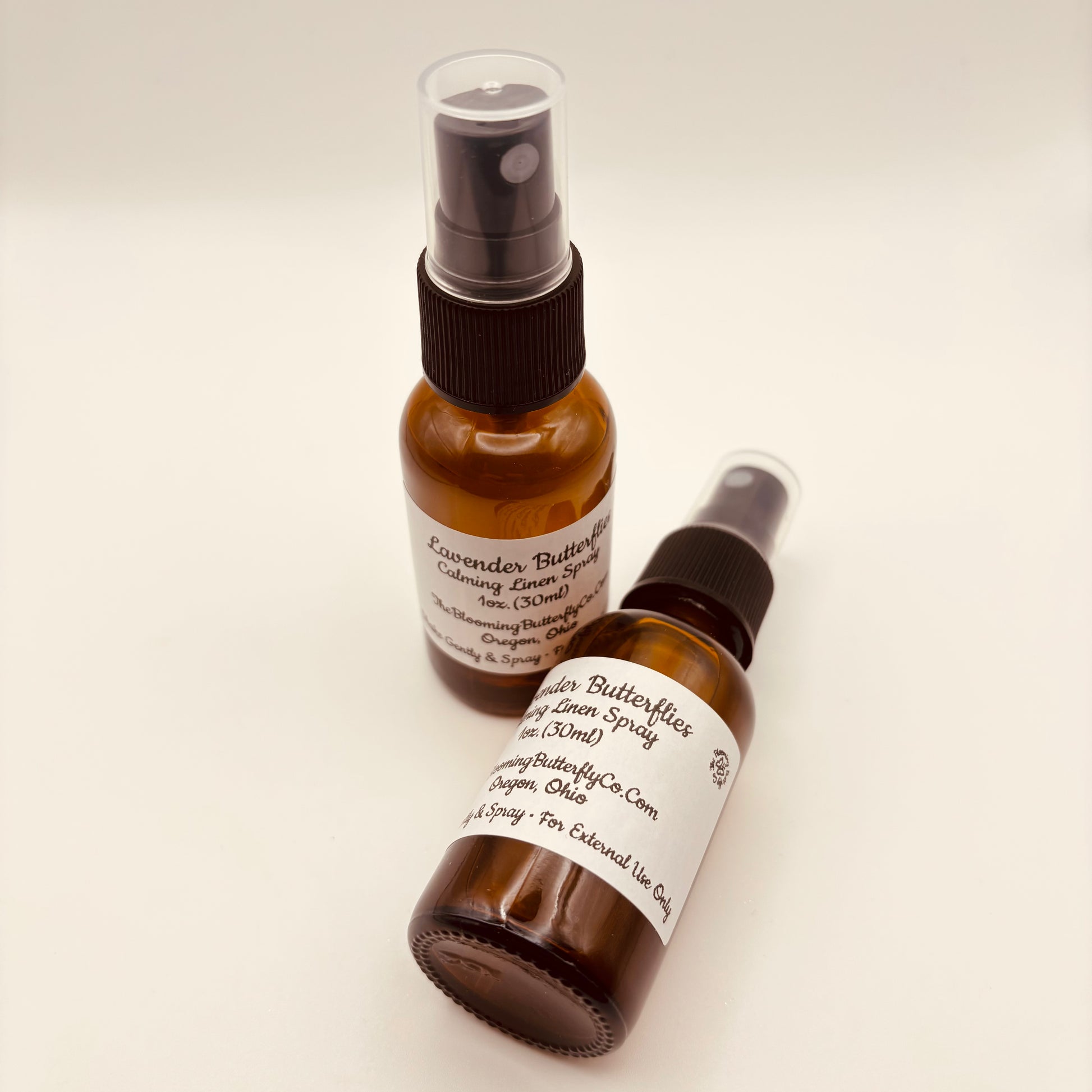 To Amber colored spray bottles of a lavender butterflies, calming linen and room spray handcrafted by the blooming butterfly company