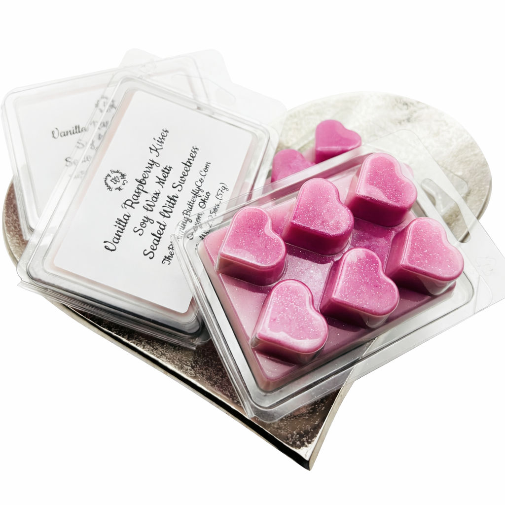 Shimmering Magenta colored wax melts scented in vanilla raspberry fragrance oil in a clear clamshell container shaped in hearts with a white label on a white background