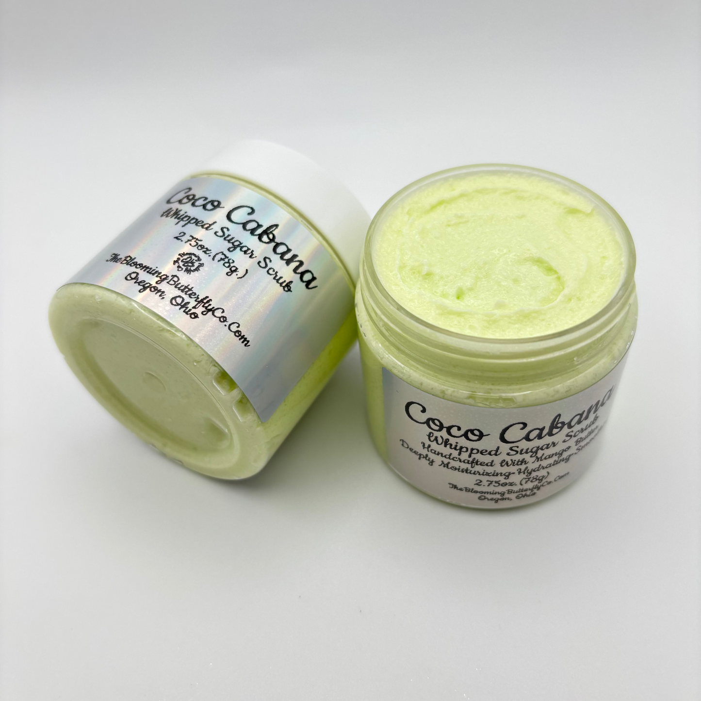 Two jars of Coco Cabana whipped sugar scrub with silver holographic labels made by the blooming butterfly company