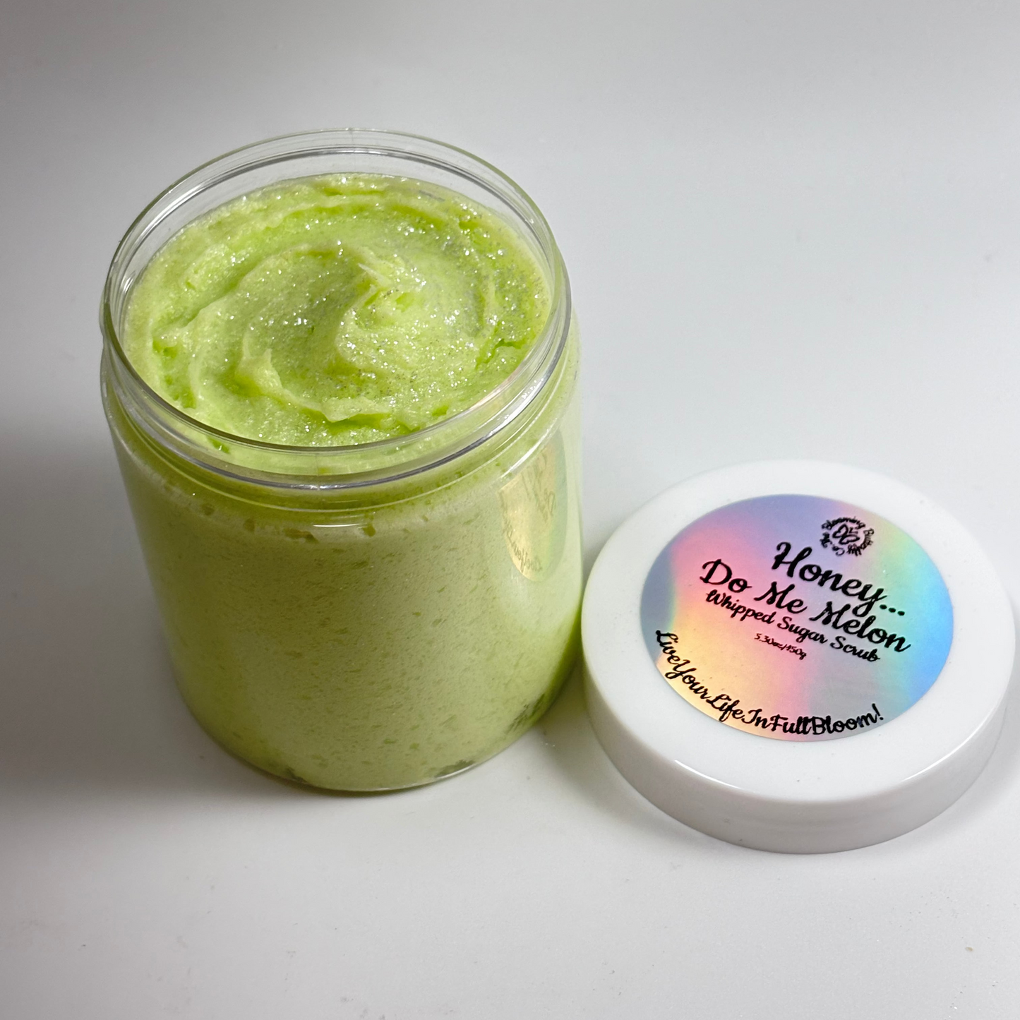 One clear jar of lime green colored honey do me melon whipped sugar, scrub with shimmering Mica on top with a white lid and holographic label handcrafted by the blooming butterfly company