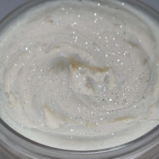 One clear close up jar of marshmallow magic shimmering, whipped body butter with sparkles on top handcrafted with mango and Shea, butters by the blooming butterfly company