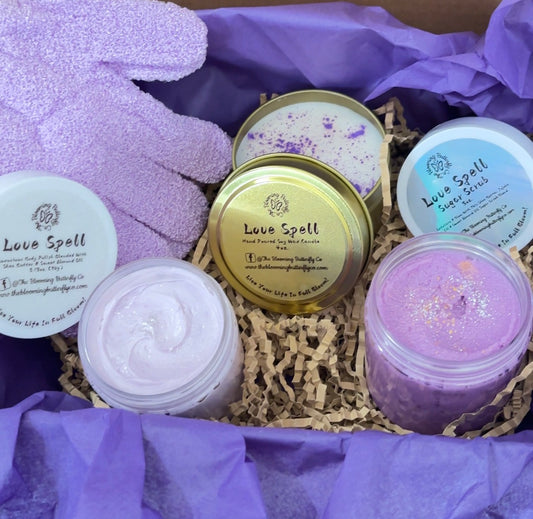  'Love Spell' bath gift set, including candle, body butter, and sugar scrub , wrapped in purple tissue paper. free pair of bath gloves or loofah