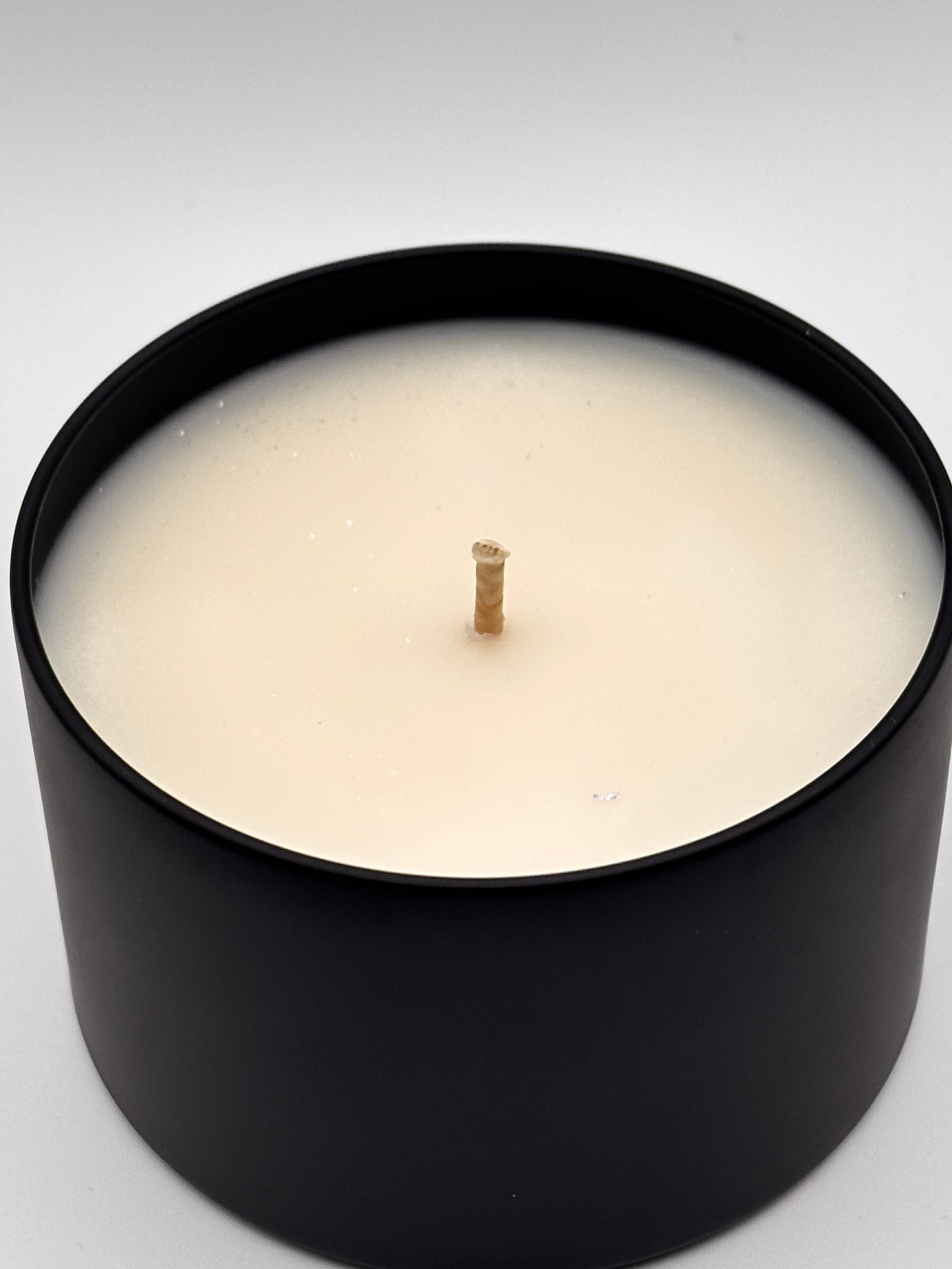christmas hearth soy wax candle in 8oz black tin with shimmering mica sprinkled on top
