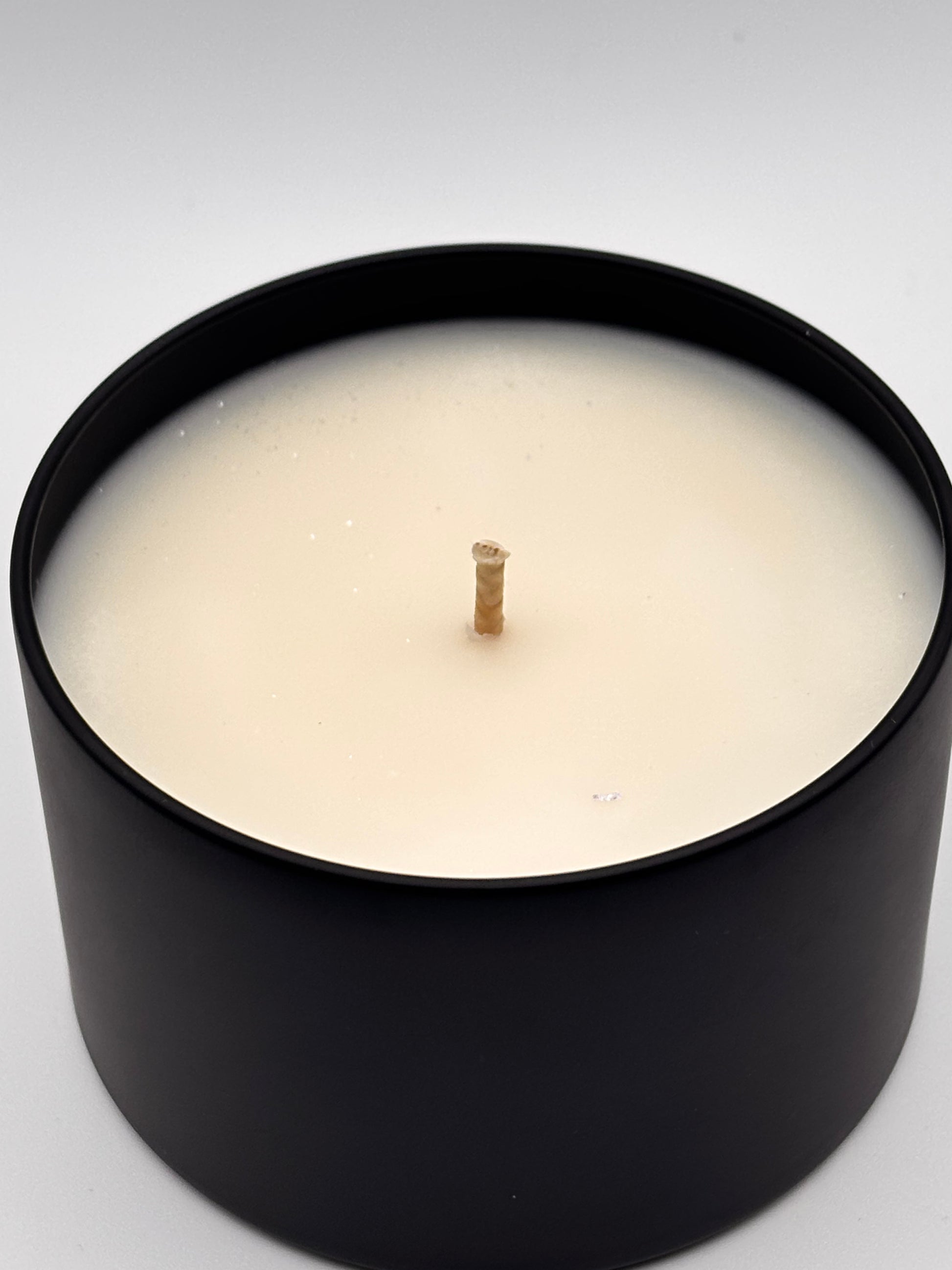 christmas hearth soy wax candle in 8oz black tin with shimmering mica sprinkled on top
