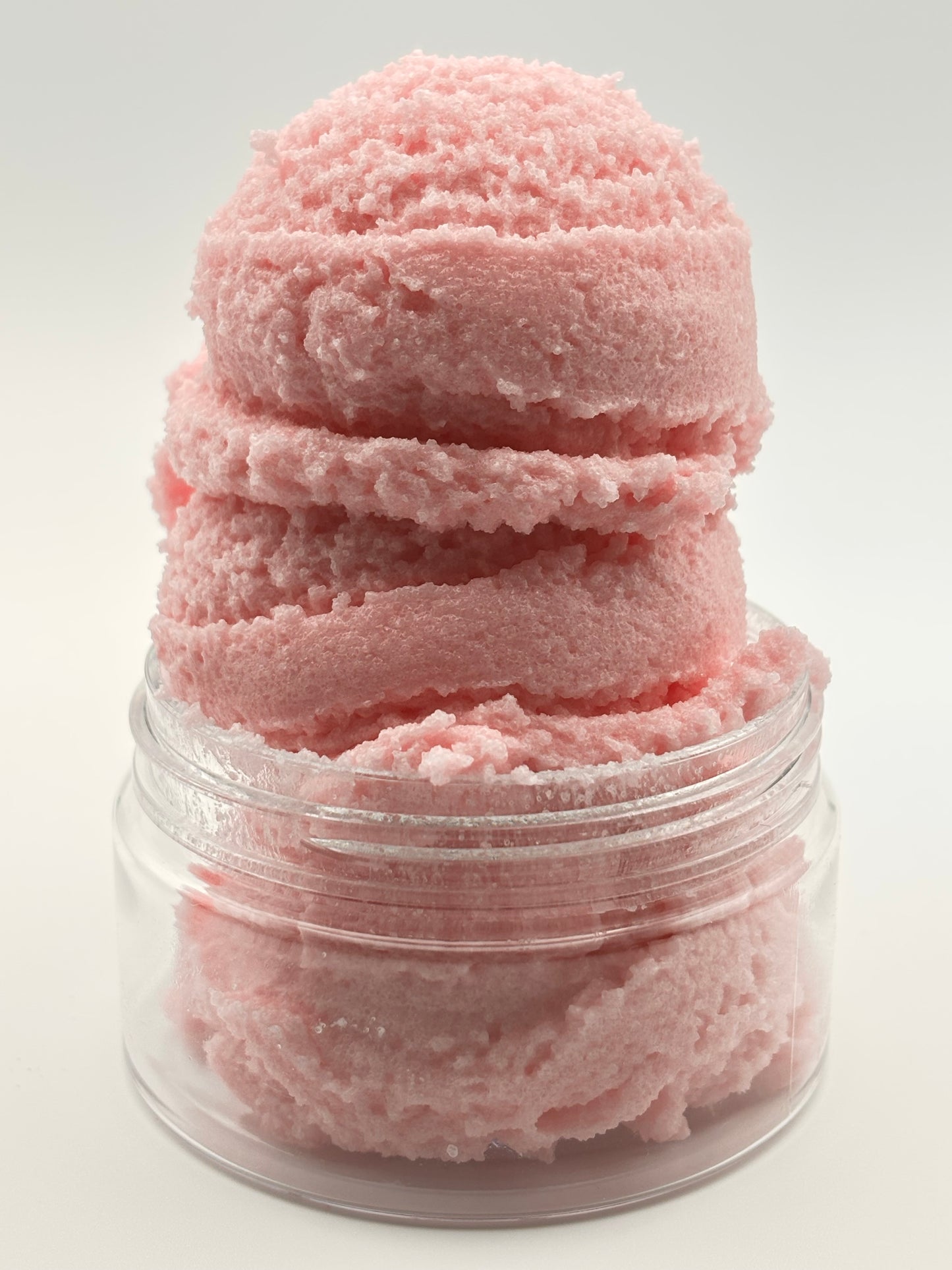 three ice cream scoops of pink sugar scrub stacked in a clear jar showing the creamy texture by the blooming butterfly company