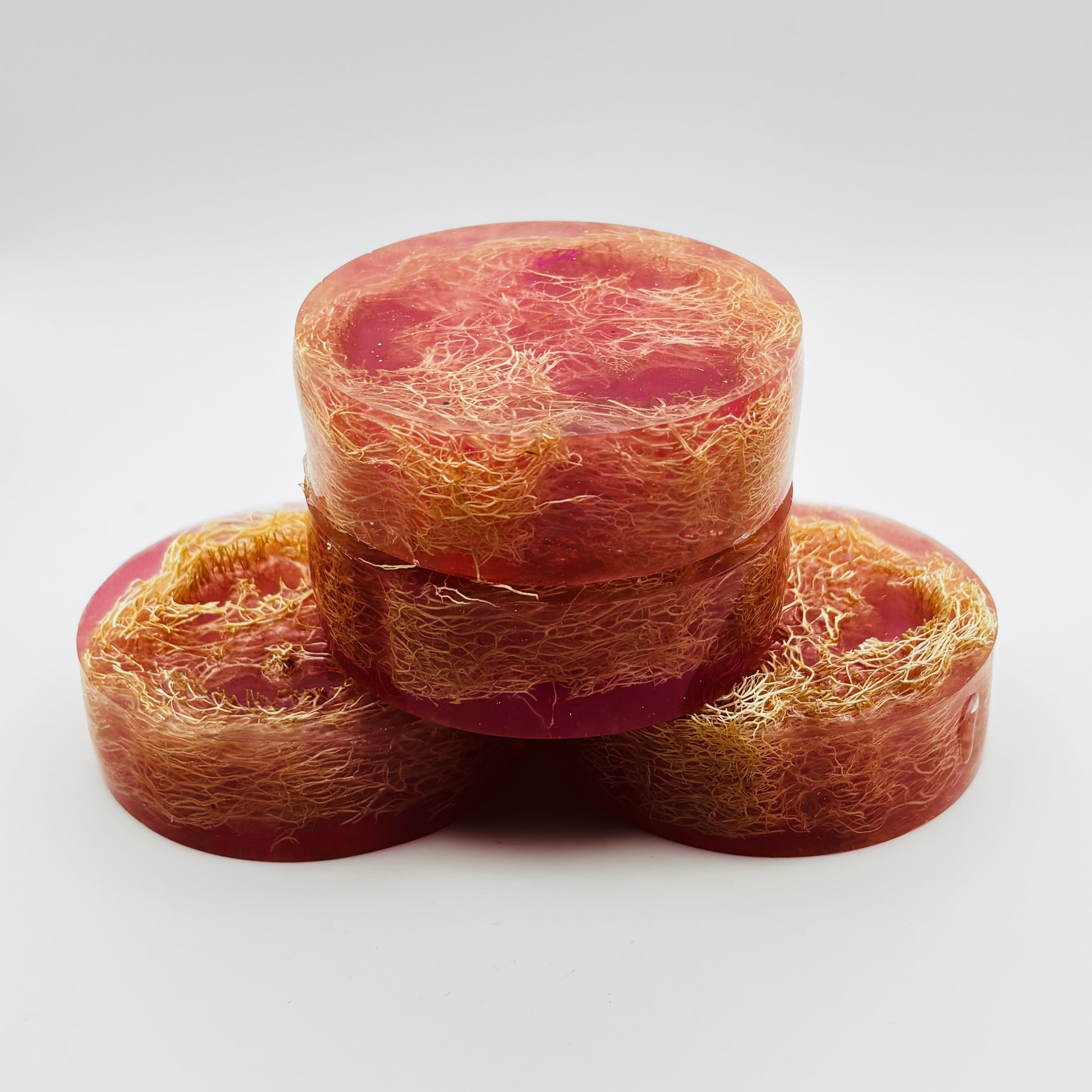 a stack of handmade loofah soap bars infused with a thousand wishes fragrance oil, shimmering magenta colored mica and organically grown loofahs