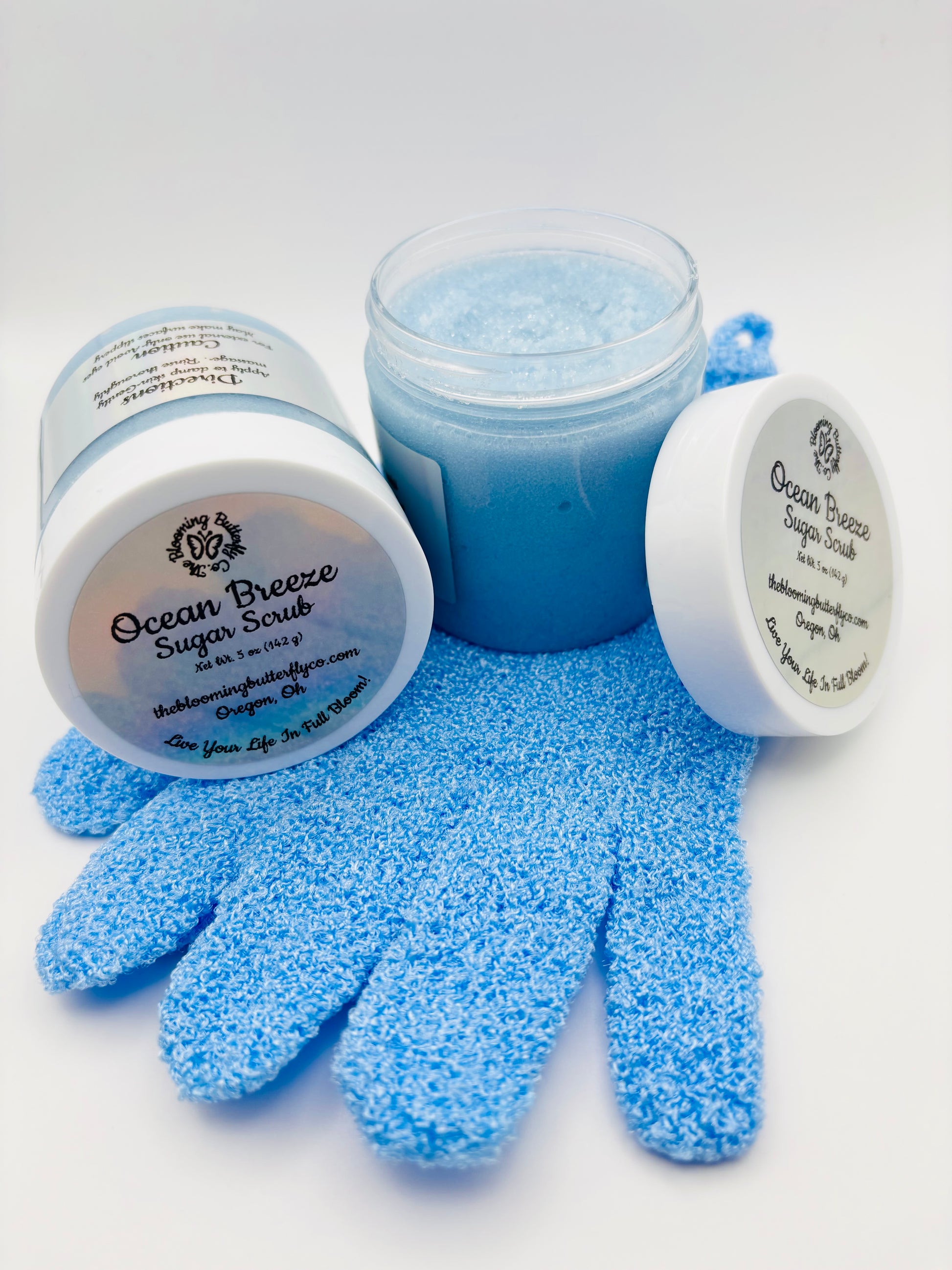 Two blue jars of Ocean Breeze Sugar Scrub with gloves and holographic labels handcrafted by the blooming butterfly company