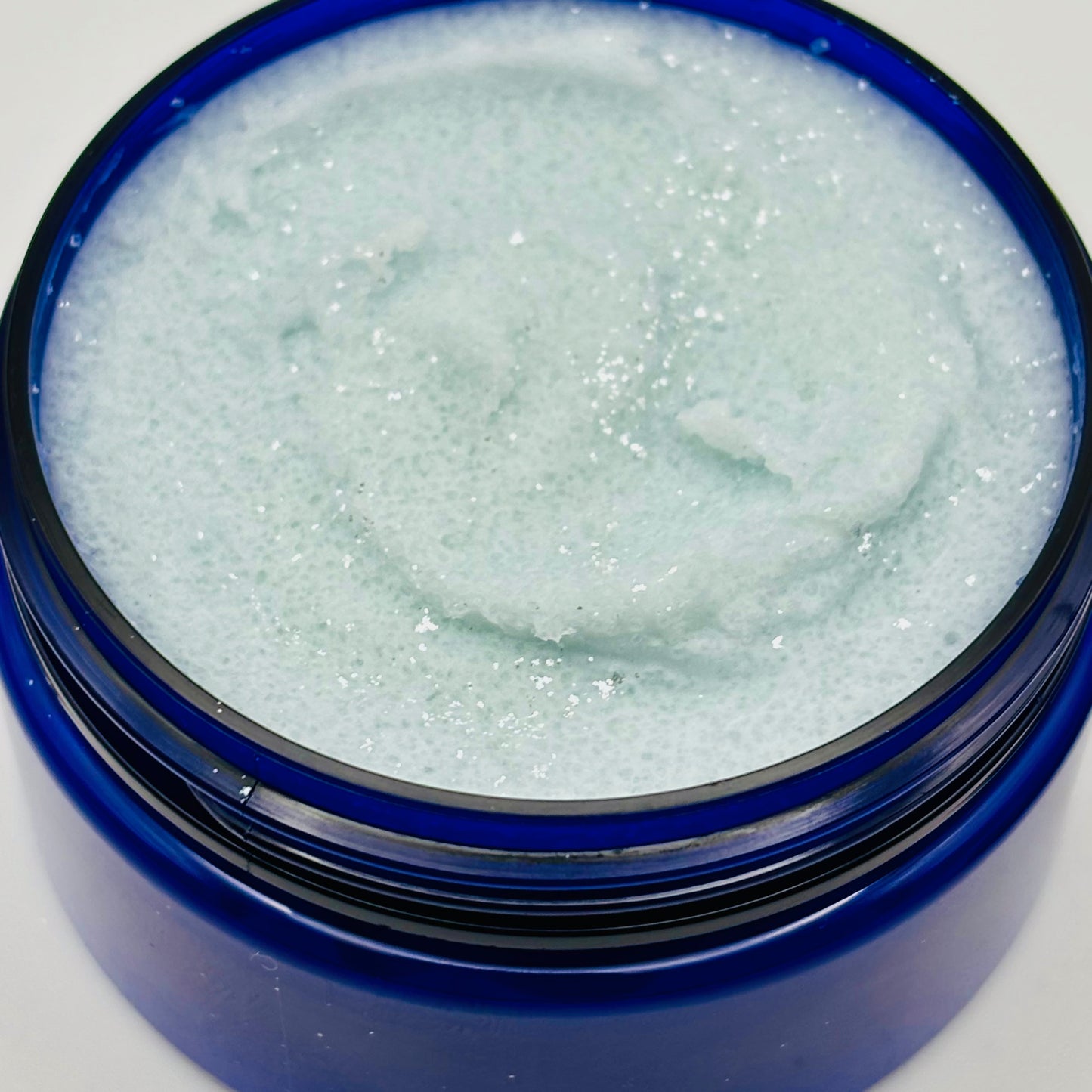 Blue container with a close up photo of blueberry kisses sugar scrub inside on a white background handcrafted by the blooming butterfly company