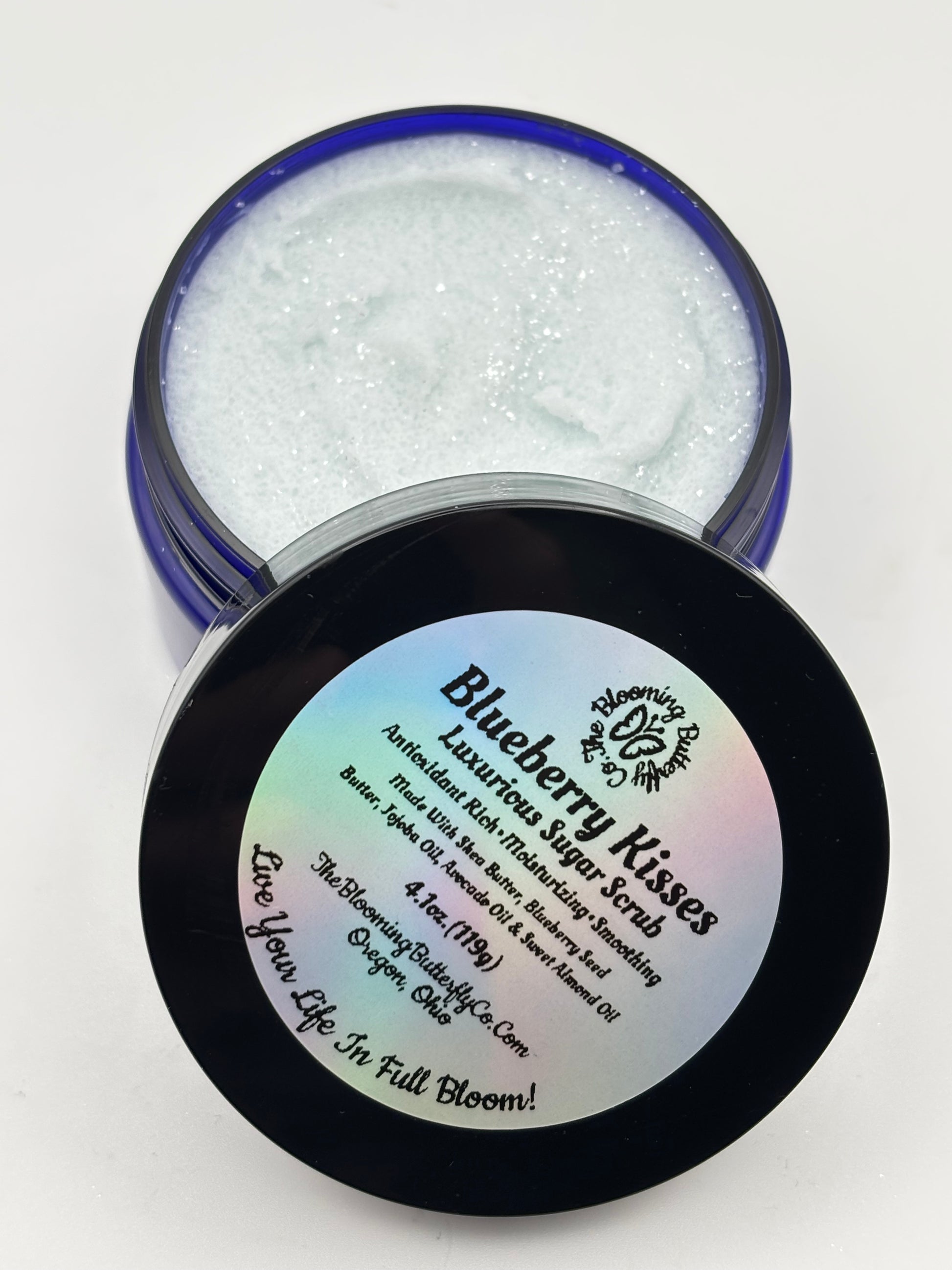 Blueberry Kisses luxurious sugar scrub in open jar with lid on a white background handcrafted by the blooming butterfly company