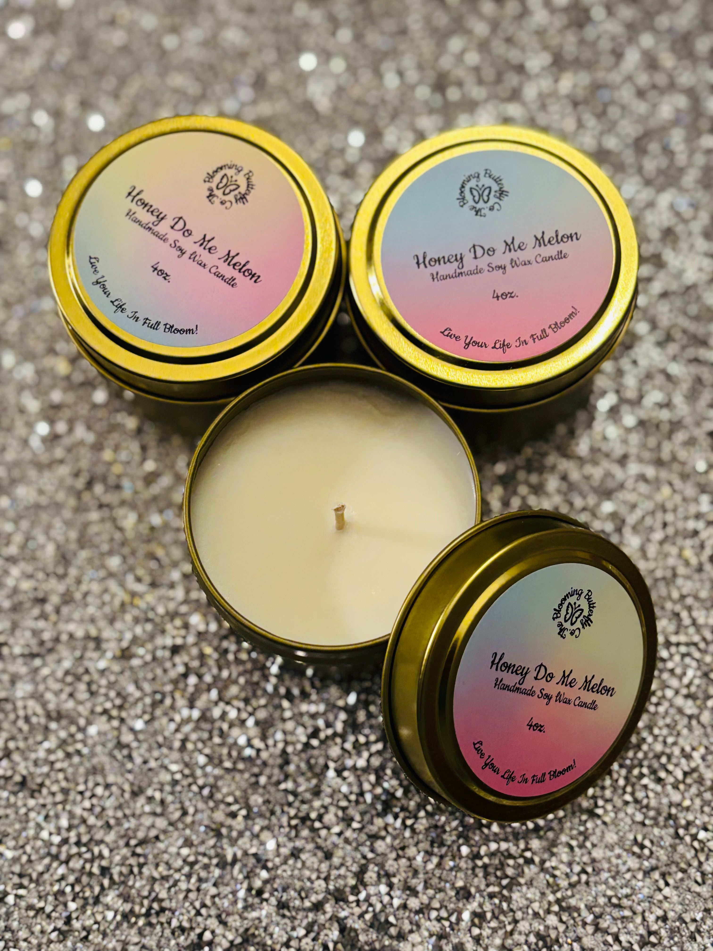 Three 'Honey Do Me Melon' candles with gold lids on a glittery surface